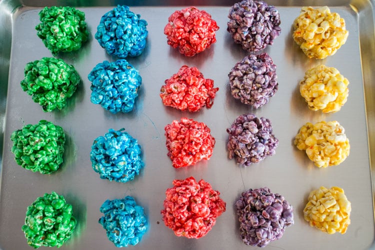How to Make Popcorn Balls with marshmallow! This easy DIY recipe walks you through how to make colored popcorn balls using food dye and karo syrup! They're a great snack and dessert for birthday parties!