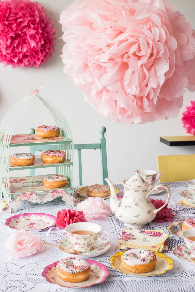 donuts, tea cups and plates on table for tea party