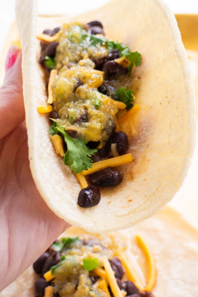 black bean tacos with cheese and salsa on top.