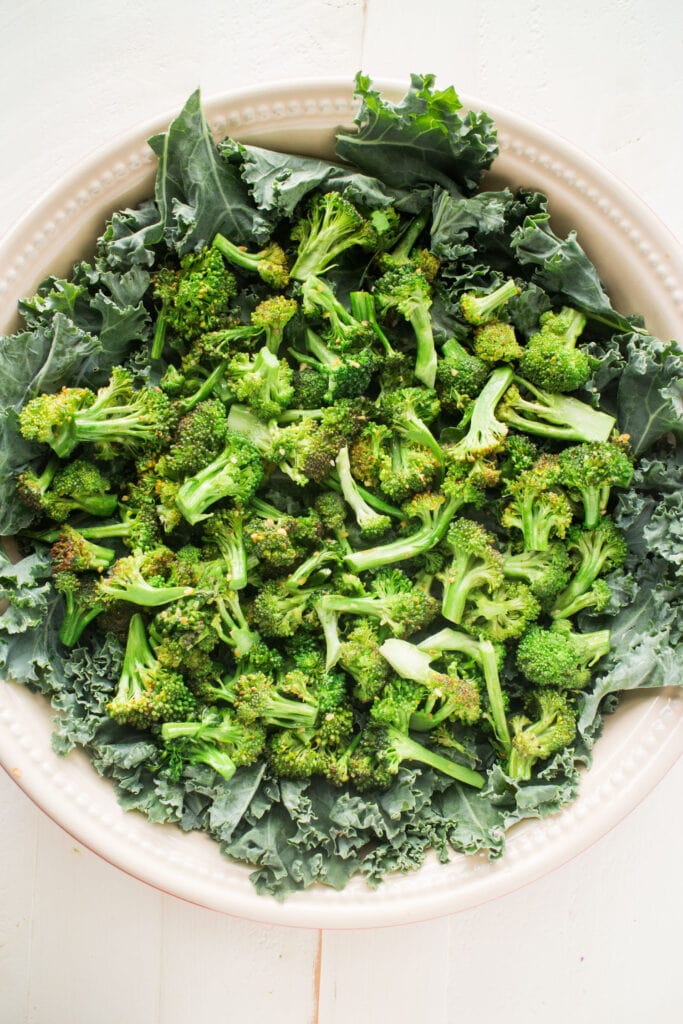 broccoil and garlic on top of kale in baking dish.
