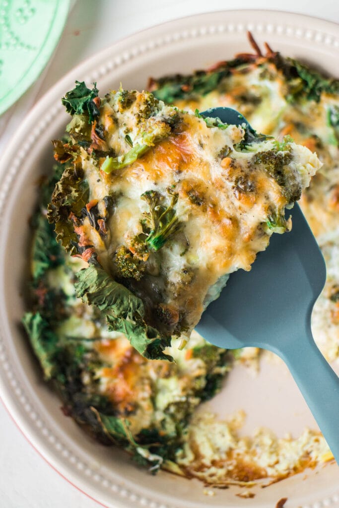 Spatula lifting up a piece of broccoli and cheese quiche. 
