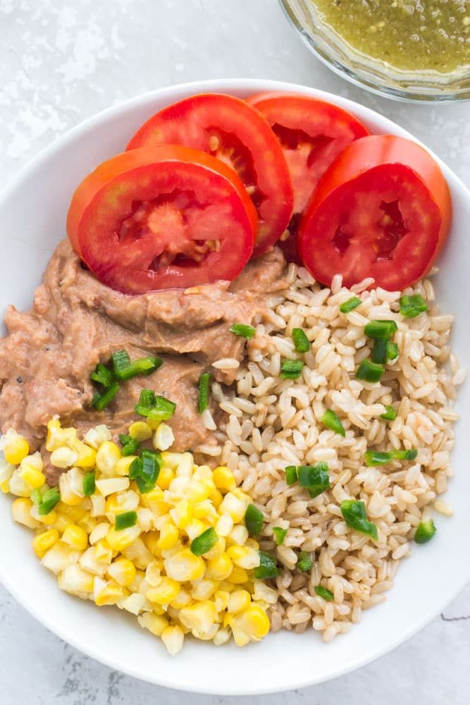 Vegetarian Mexican Burrito Bowl that includes rice, refried beans, corn, tomato, pepper and salsa.  Perfect for work lunches or quick dinners as it only takes 5 minutes to make!