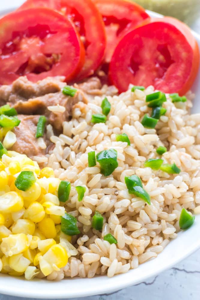 Vegetarian Mexican Burrito Bowl that includes rice, refried beans, corn, tomato, pepper and salsa. Perfect for work lunches or quick dinners as it only takes 5 minutes to make!
