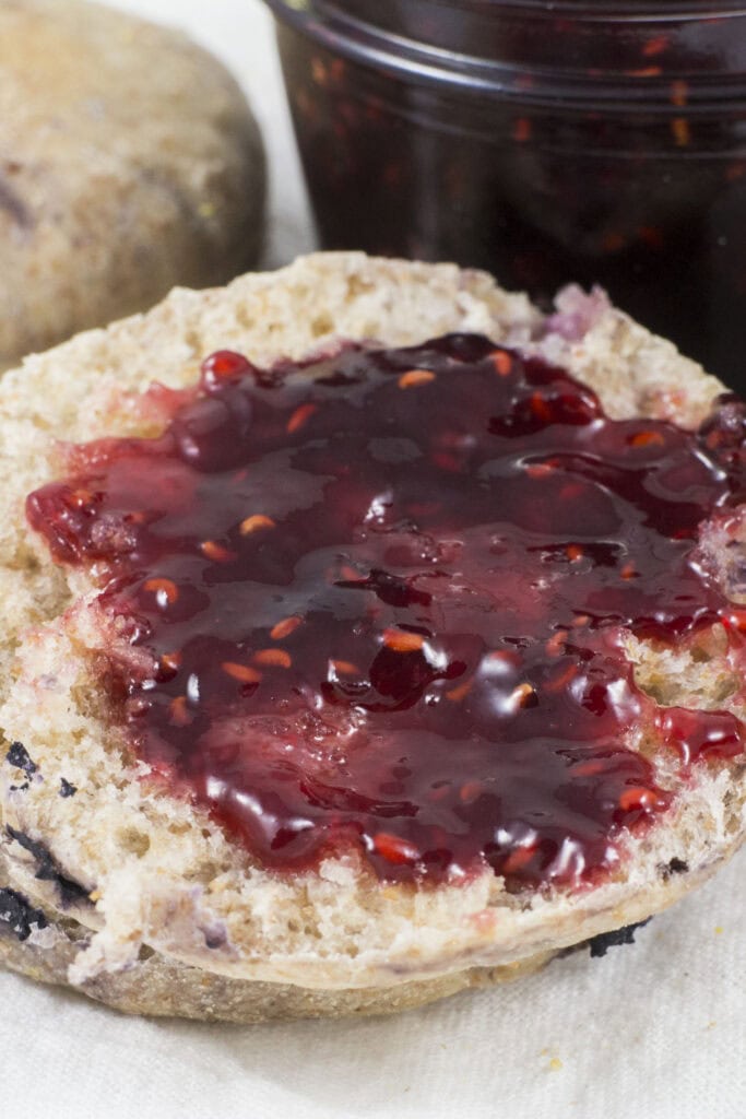 raspberry jam spread out on blueberry english muffin.