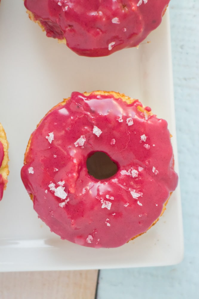 These donuts are so pretty and yummy! Gluten Free Baked Vanilla Donuts recipe with a bright pink frosting on top! The icing glaze is completely all natural and made with beet powder - which has no beet taste to it! These cute donuts are great for birthday party, bridal party and wedding desserts!