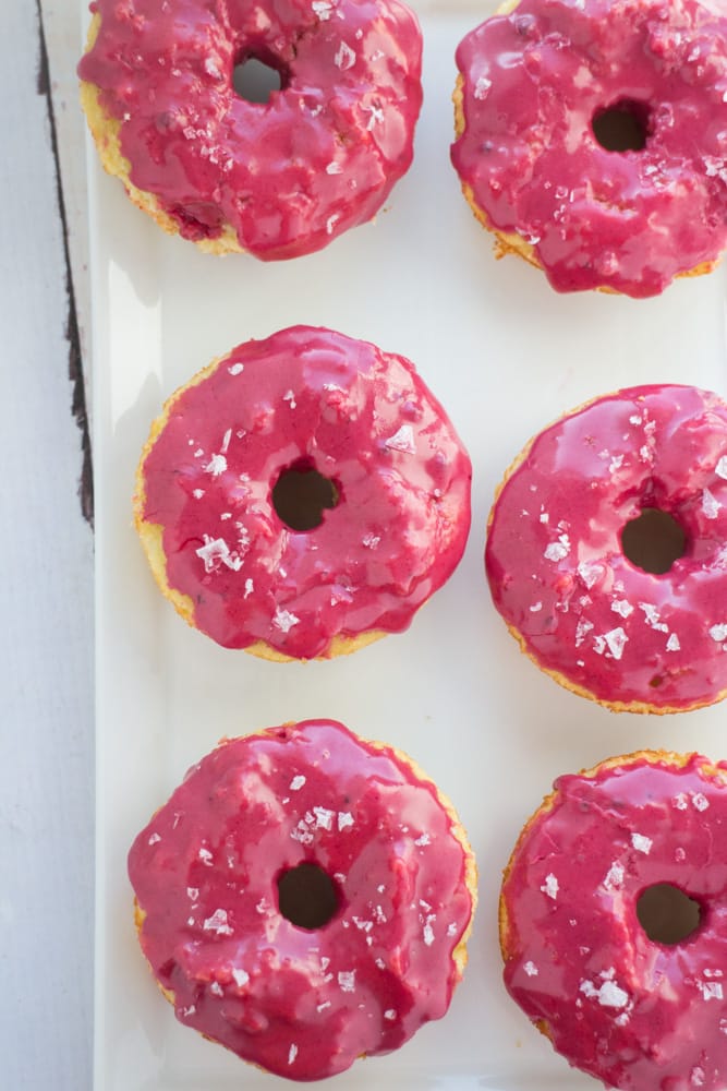 These donuts are so pretty and yummy! Gluten Free Baked Vanilla Donuts recipe with a bright pink frosting on top! The icing glaze is completely all natural and made with beet powder - which has no beet taste to it! These cute donuts are great for birthday party, bridal party and wedding desserts!