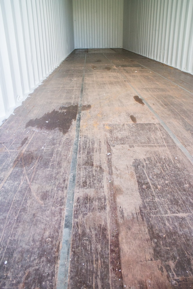 How to remodel a shipping container's floor to make it move in ready. Find out how to easily refinish the floors on a budget to turn it into your modern dream home! Great design inspiration and cost info for your shipping container house! 