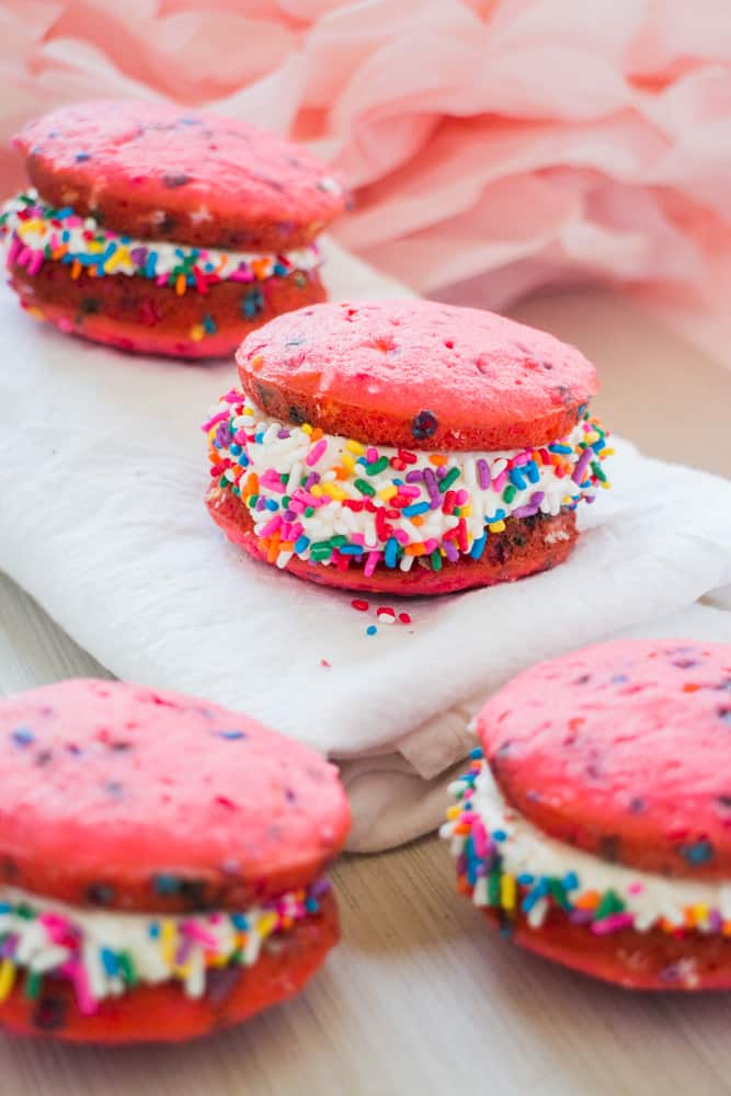 It's time to celebrate with these classic Vanilla Whoopie Pies! This easy recipe makes delicious vanilla whoopie cake pies with marshmallow creme filling (just like homemade Amish Whoopie Pies!). These pretty treats are perfect for a birthday party or baby shower celebration (Its a girl!) with the help of pink food coloring and rainbow sprinkles. 