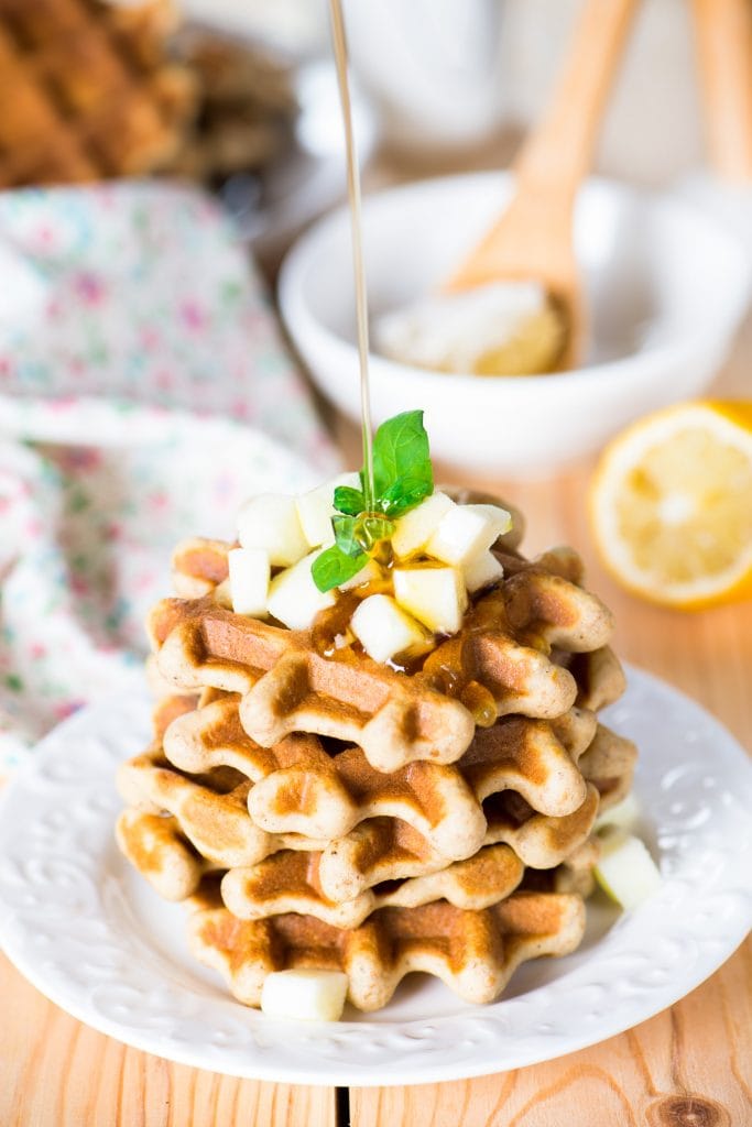 syrup being poured on top of stack of apple waffles.