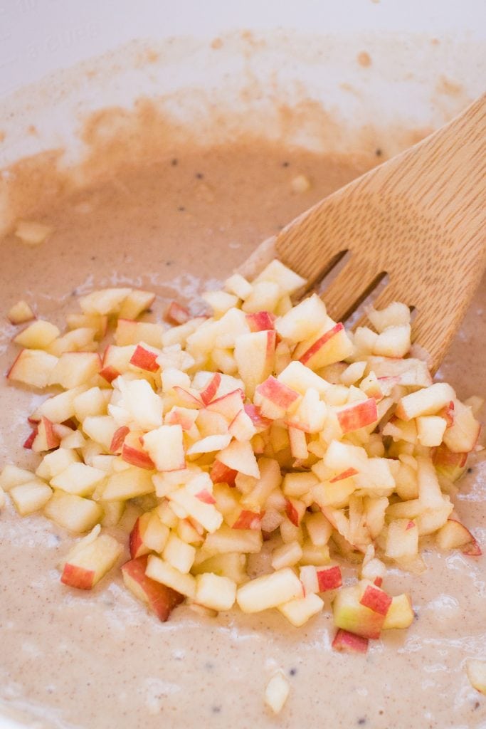 apples being mixed in bowl with batter.