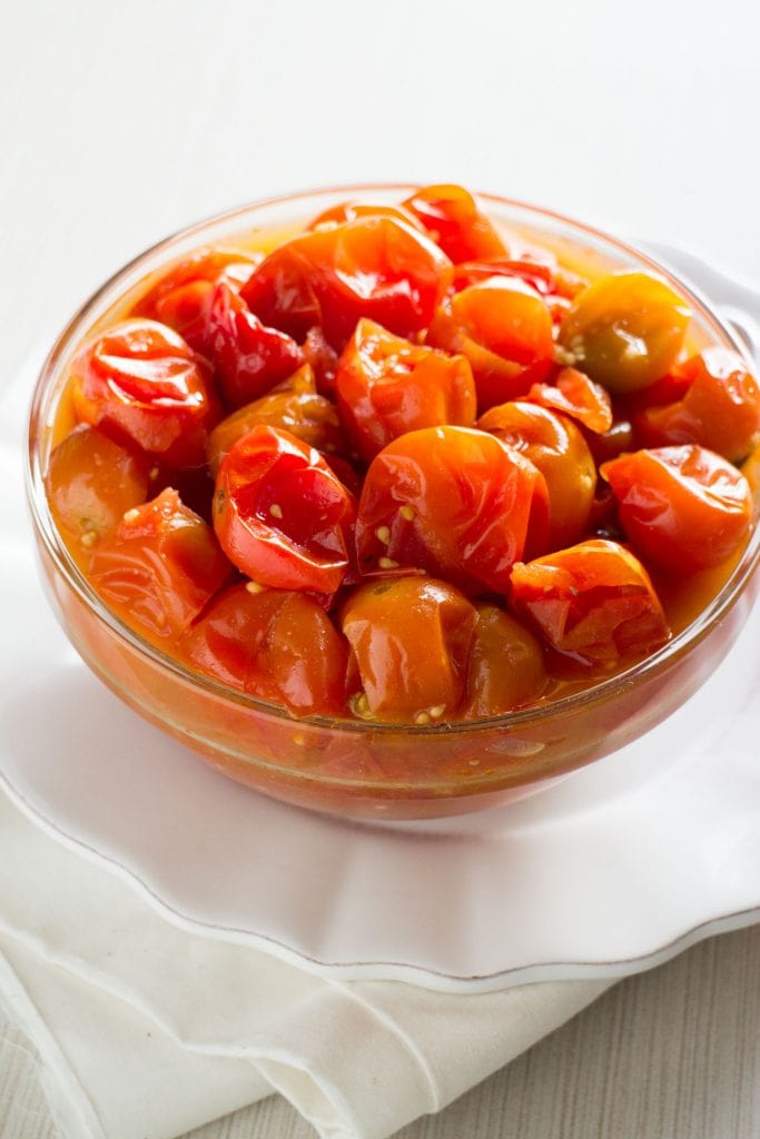 cooked cherry tomatoes in glass bowl on white plate