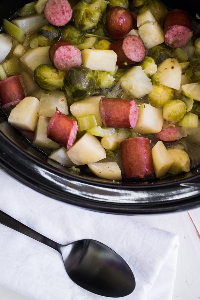 FAMILY FAVORITE Slow Cooker Kielbasa, Brussels Sprouts and Potatoes! This healthy dinner is so easy to make as it only takes 5 hours in the crock pot! The meal cooks in a beef broth brown sugar mix that is amazing! It's one of my family's favorite comfort food recipes for a Winter night! We love serving it over egg noodles or rice!