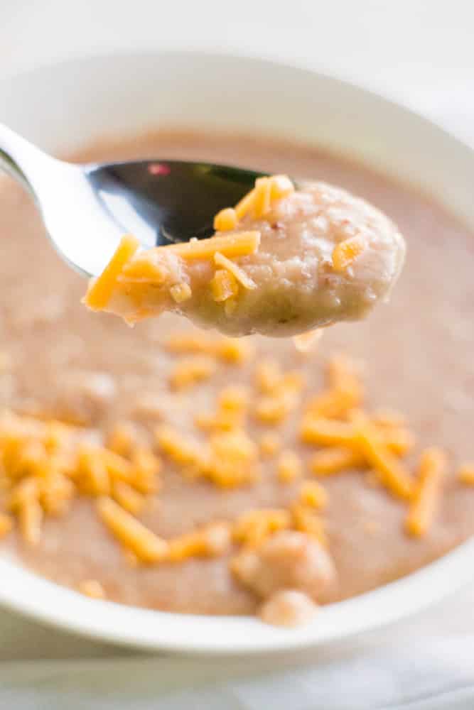 DELICIOUS, NO SOAKING REQUIRED, Slow Cooker Refried Beans! This easy homemade refried beans recipe cooks dry pinto beans in the slow cooker! They make the perfect tasty side dish for authentic Mexican meals. You’ll never use canned beans again! 