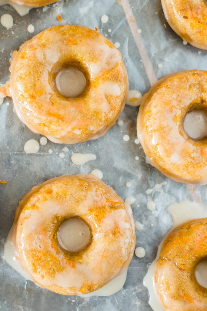 mulitple glazed carrot donuts on parchment paper.
