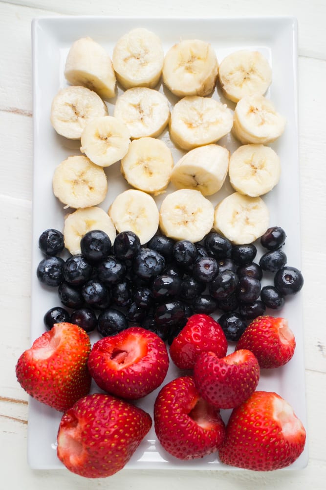 bananas, blueberries and strawberries on plate.