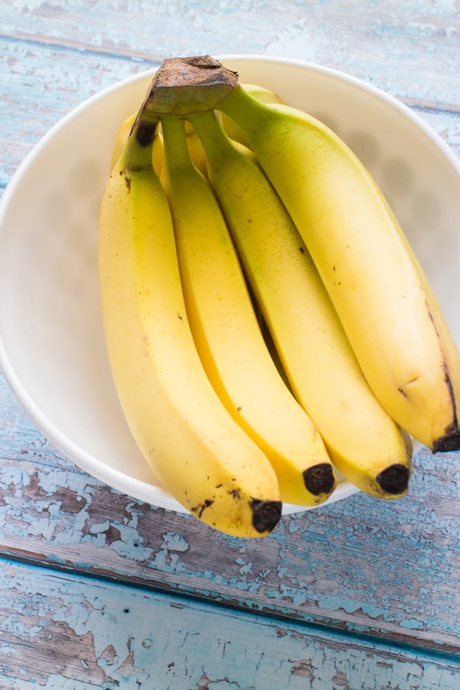 How to Store Bananas!  These easy tips will prevent your bananas from turning brown!  Tricks includes storing with other fruit, plastic wrap, banana trees and how to freeze bananas!  Learn the best ways to store bananas and keep them green for longer!