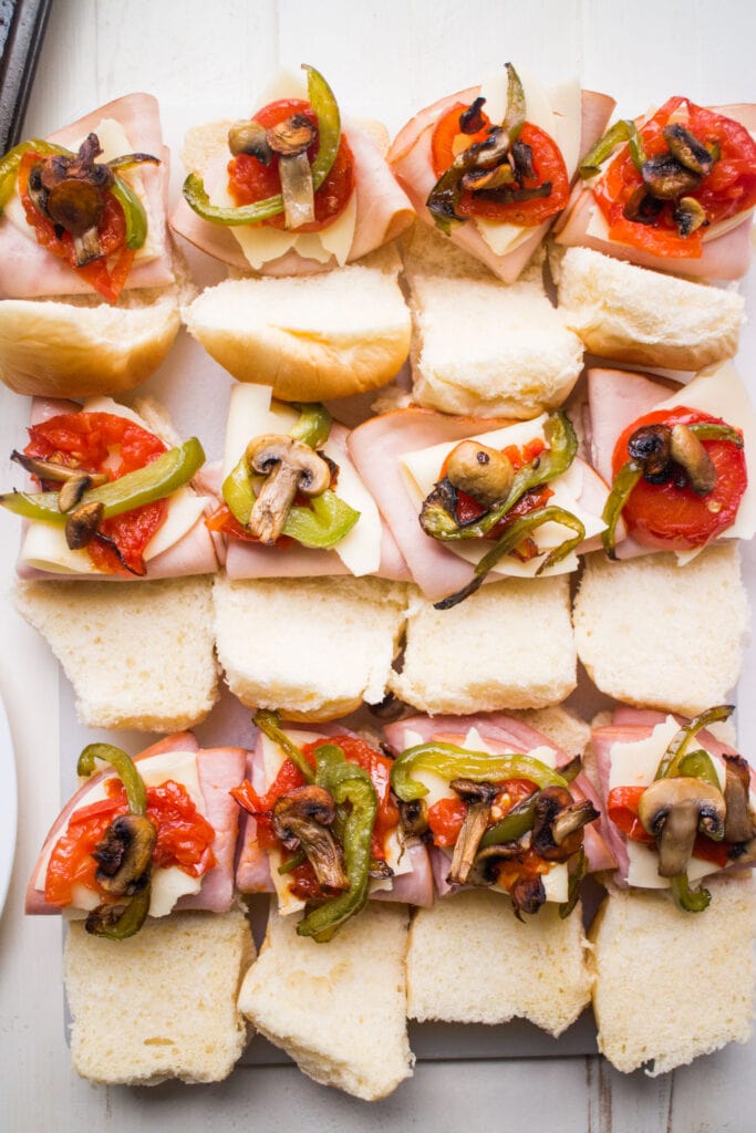 slider sandwiches with meat and vegetables on it.