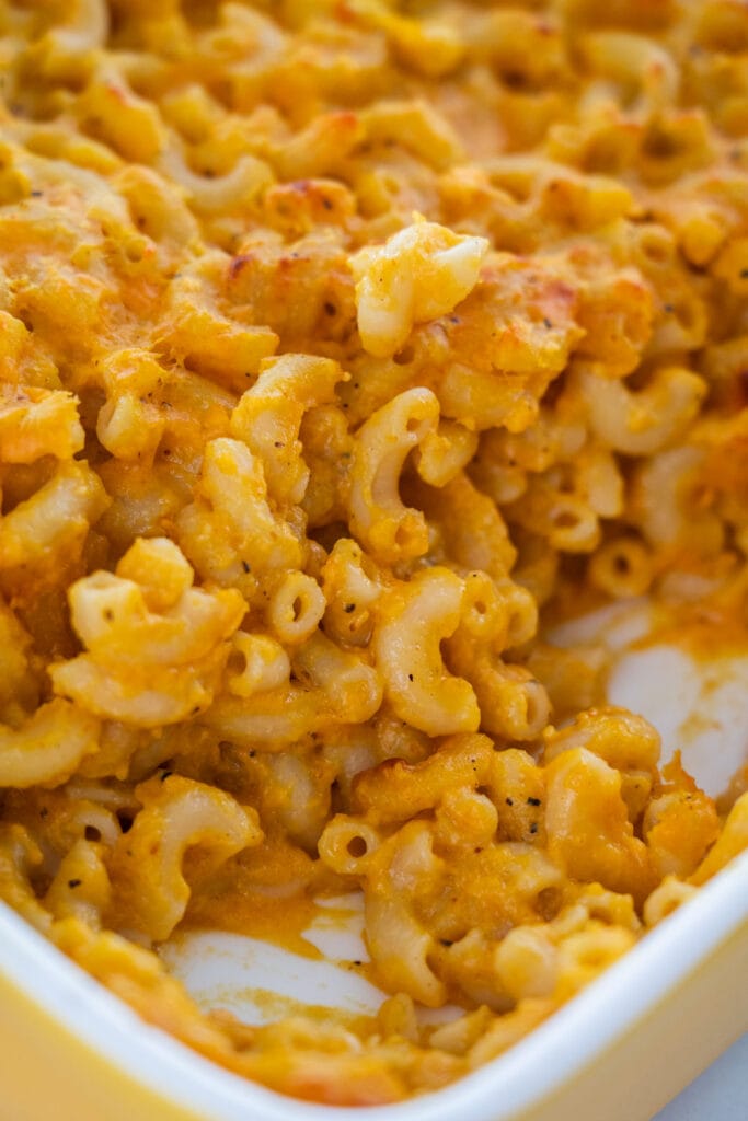pumpkin mac and cheese in baking dish with some scooped out.