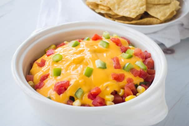 HEALTHY 7 Layer Taco Dip is easy to make with tomatoes, corn, lettuce, pinto refried beans, green pepper, and cheese! Ready in 10 minutes! This Mexican dip is made without cream cheese and ground beef! Serve hot or cold! 