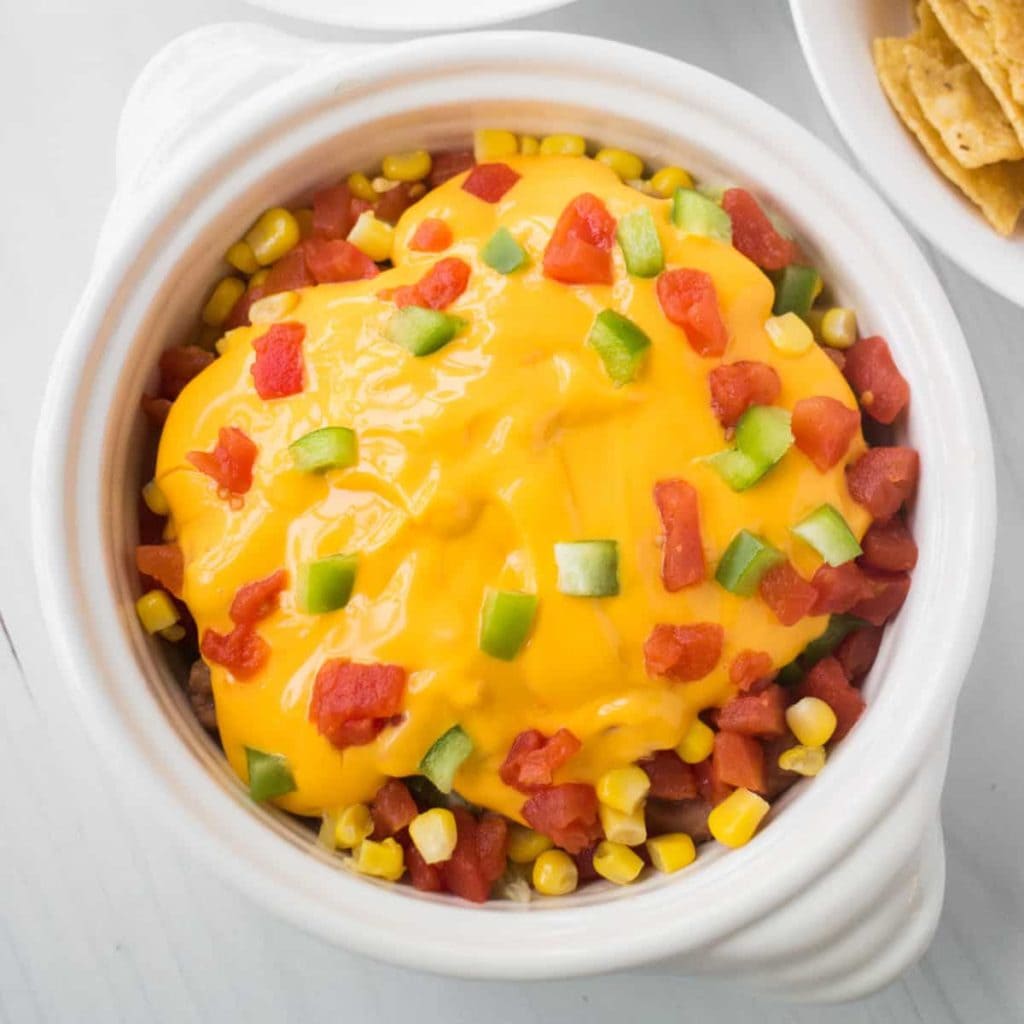 7 Layer Taco Dip is easy to make in 10 minutes with vegetables and cheese! This meatless Mexican dip is made without cream cheese for a healthy recipe.  Serve hot or cold as a party appetizer.  