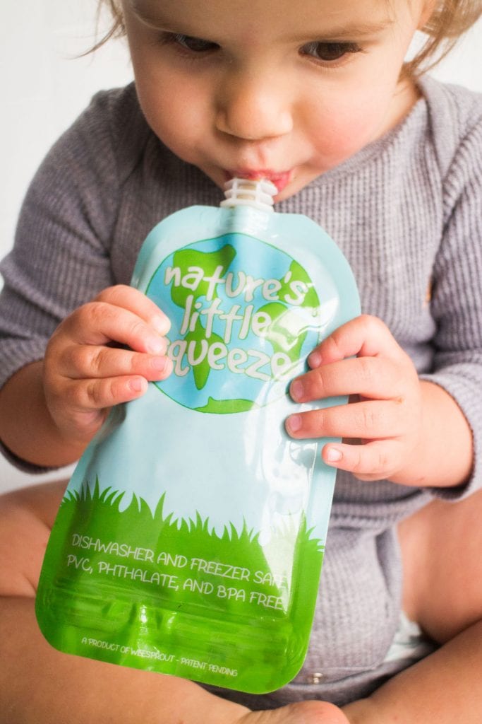 baby eating puree out of homemade baby food pouch.