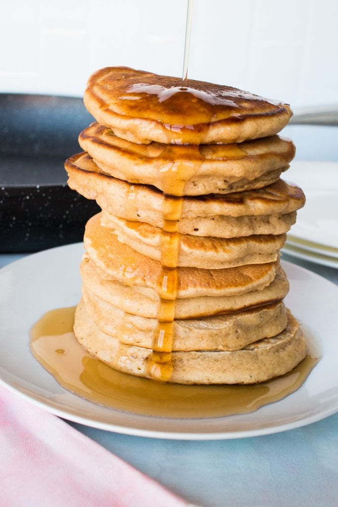 syrup being poured on stack of apple pie pancakes.