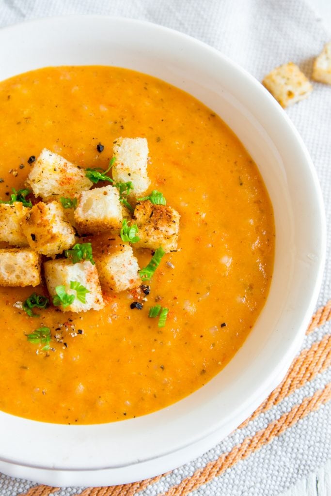 sweet pepper soup with croutons on top in white bowl. 