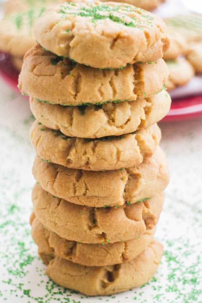 stack of peanut butter sugar cookies on table with green sugar on table.