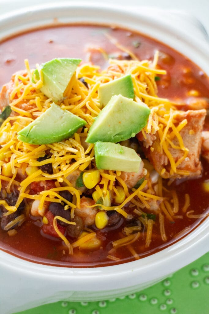 bowl filled with tortilla soup with avocado slices on top.