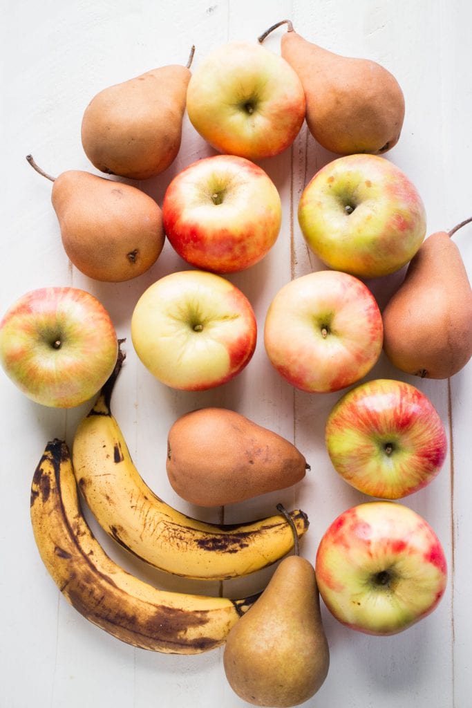 apples, pears and bananas on white table