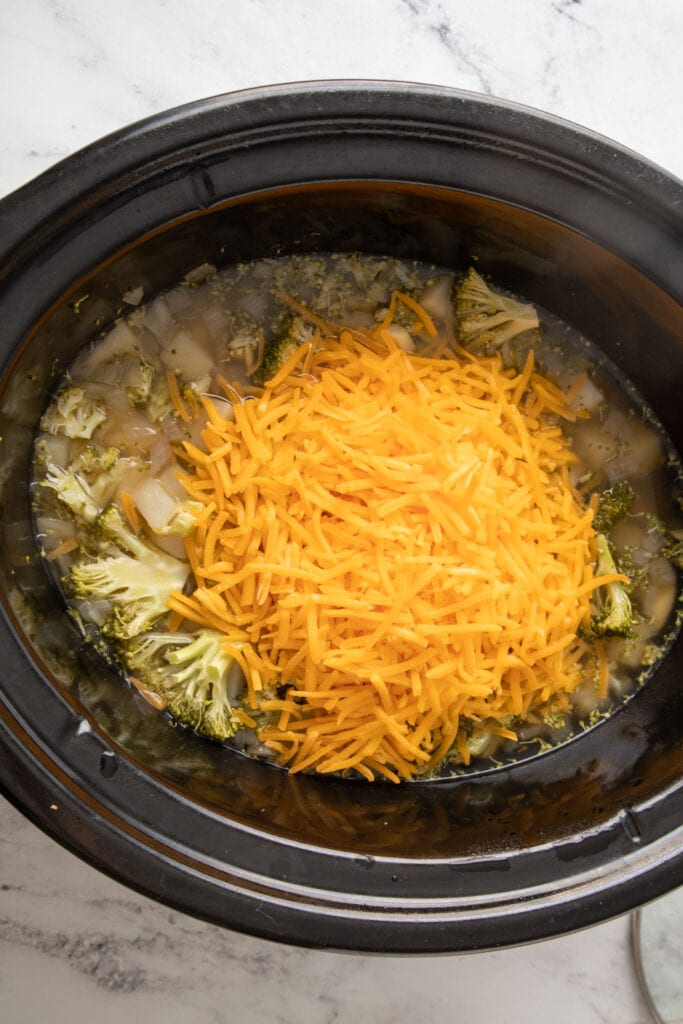 shredded cheese on top of ingredients in slow cooker.