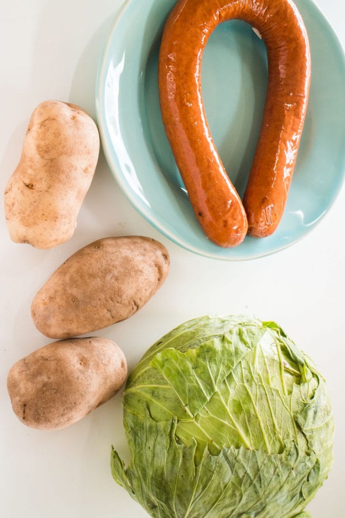 kielbasa ring, potatoes and cabbage on table.
