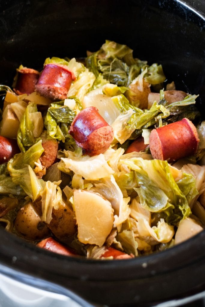 slow cooker kielbasa and cabbage cooked and ready to be served in black crockpot.