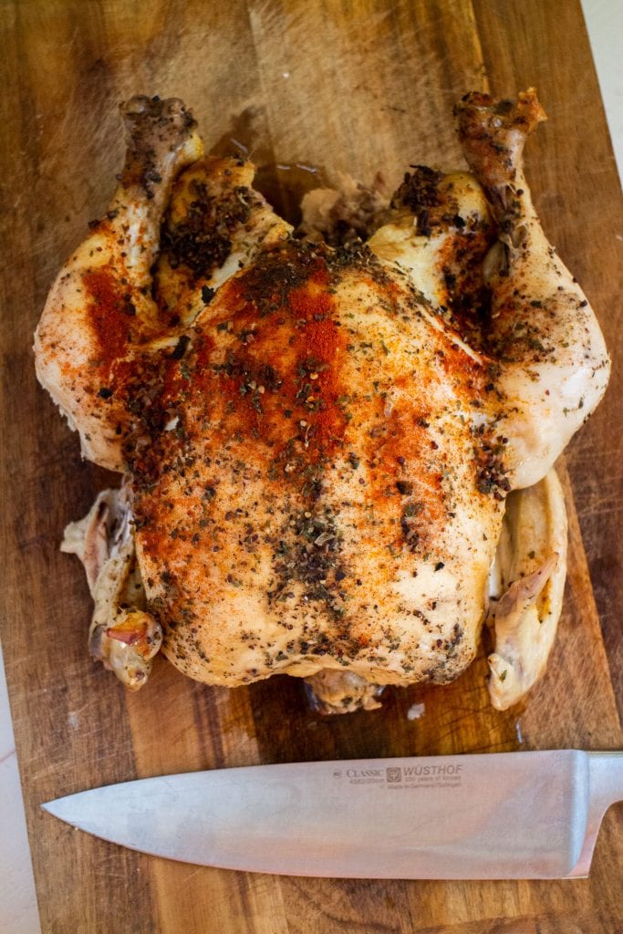 juicy whole chicken cooked in slow cooker sitting on cutting board