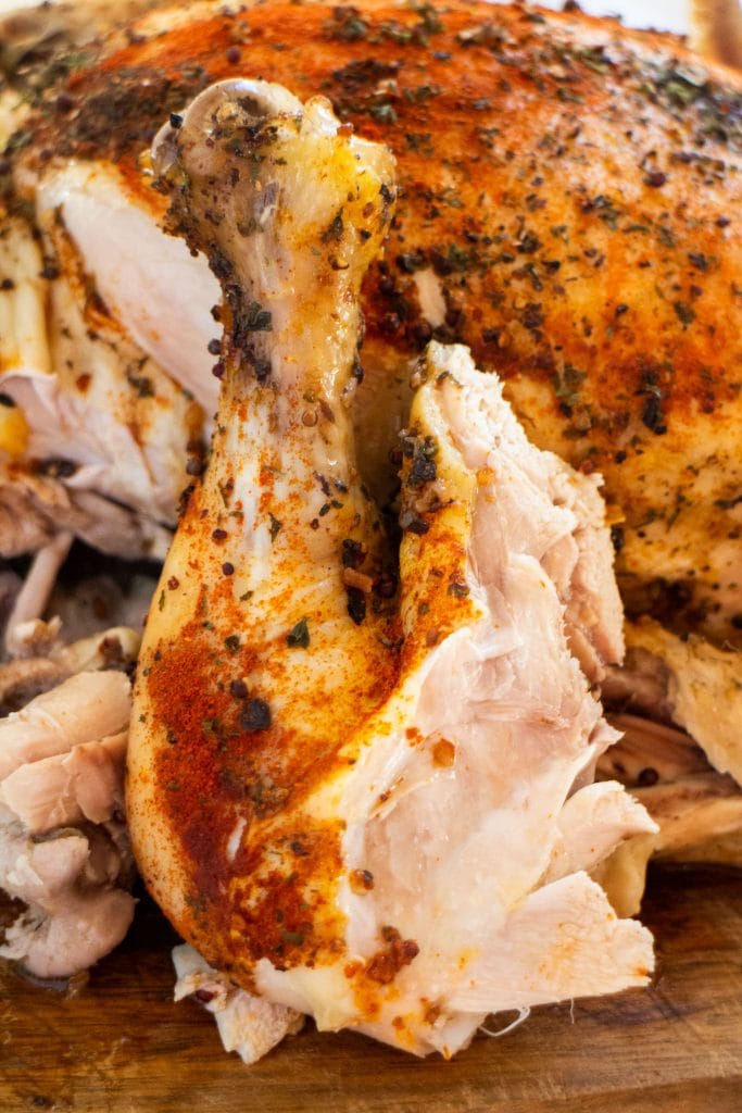 juicy chicken drumstick with skin on it placed in front of whole chicken