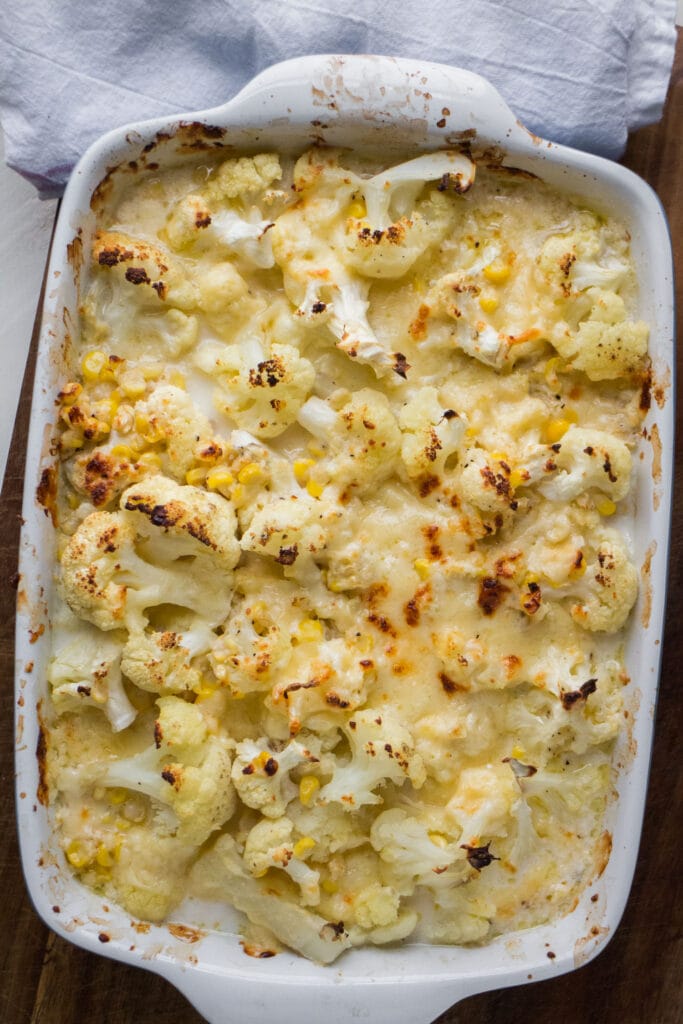 baked cauliflower covered in cheese in white baking dish.