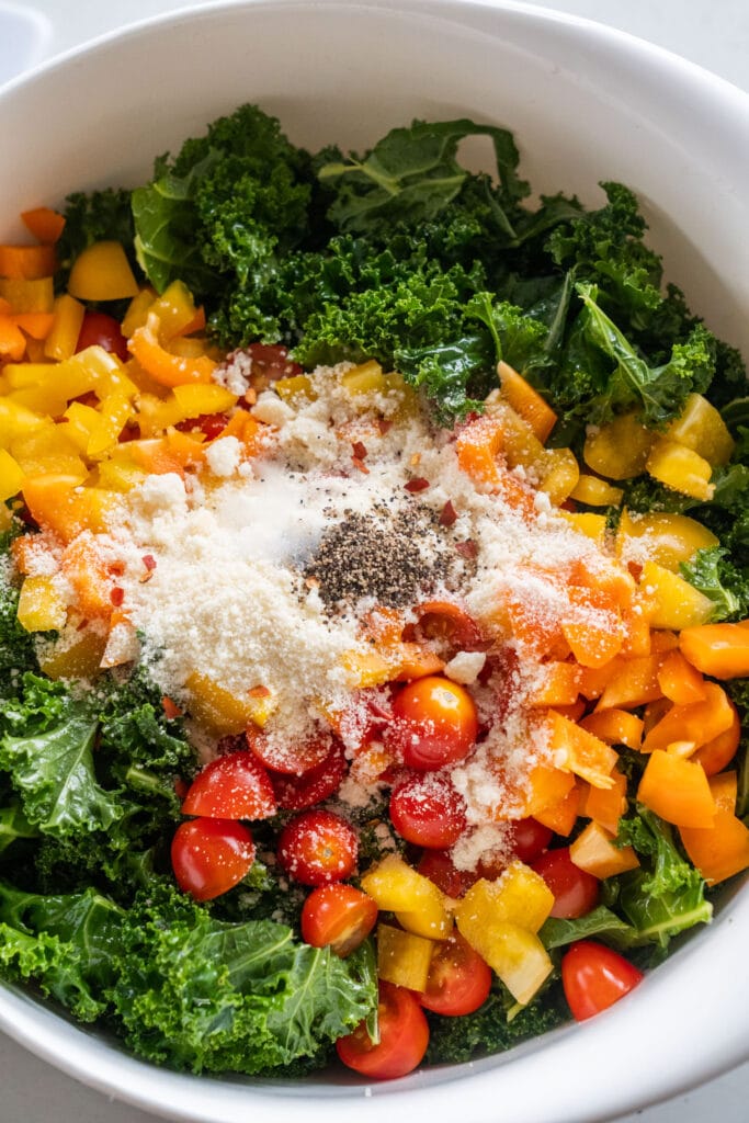 Parmesan cheese and seasonings in bowl with kale and vegetables.