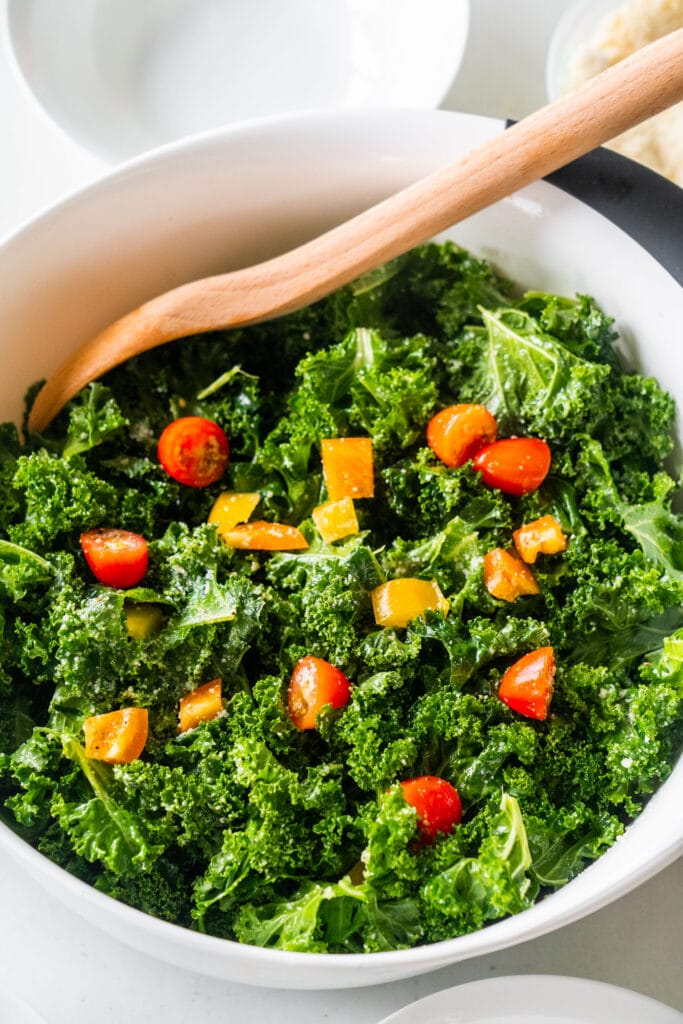 bowl of kale salad with wooden spoon in it.