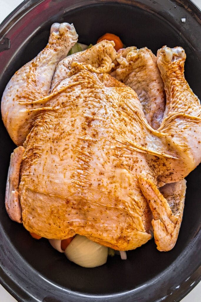 whole chicken with spices on it in slow cooker.