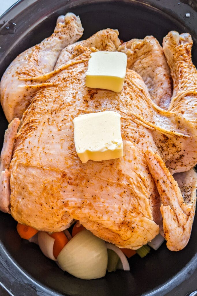 pats of butter on top of chicken in slow cooker. 