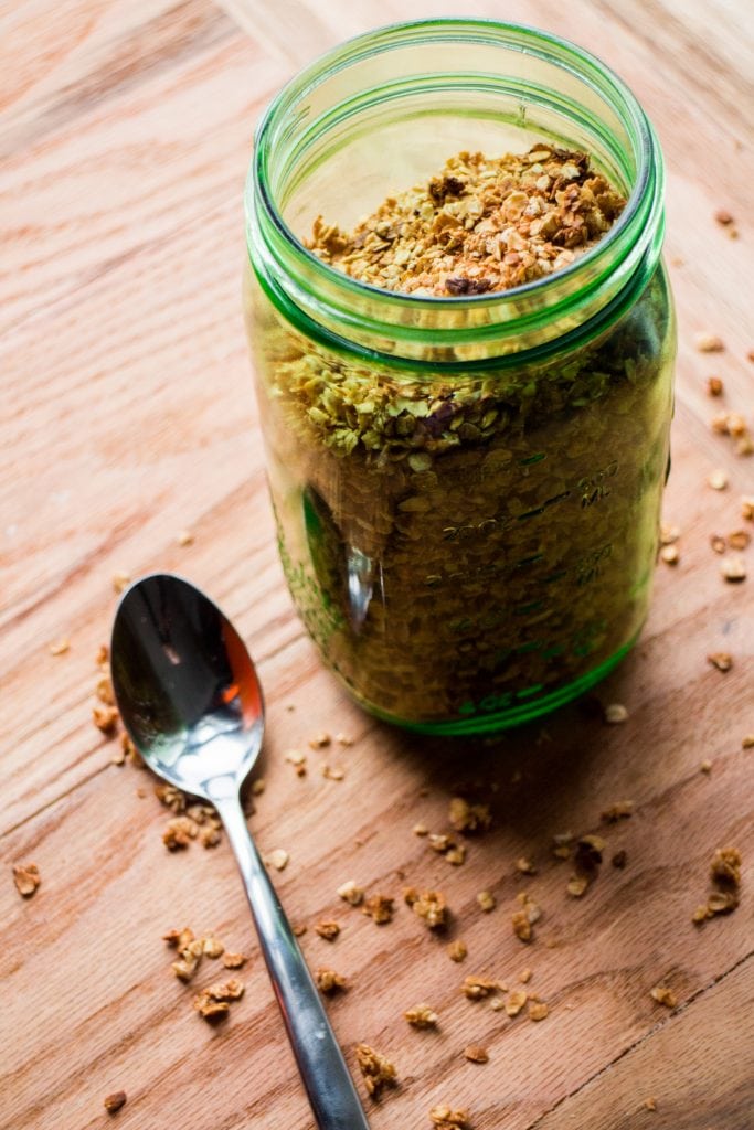 mason jar filled with granola with spoon next to it.