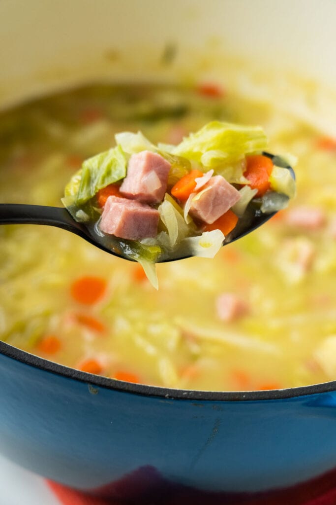 spoon filled with cabbage and ham soup.
