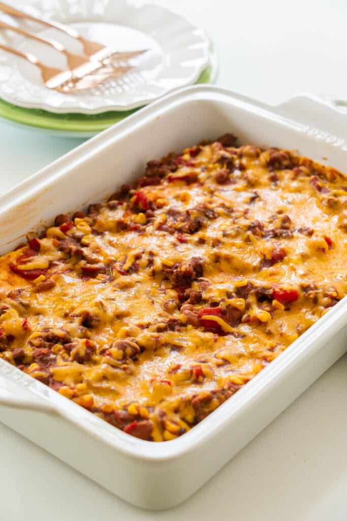 baked casserole on table with plates behind it.