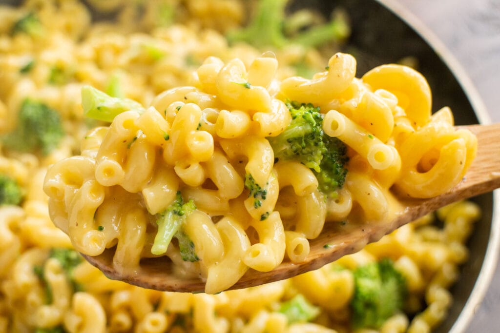 spoon holding broccoli mac and cheese, ready to be served.