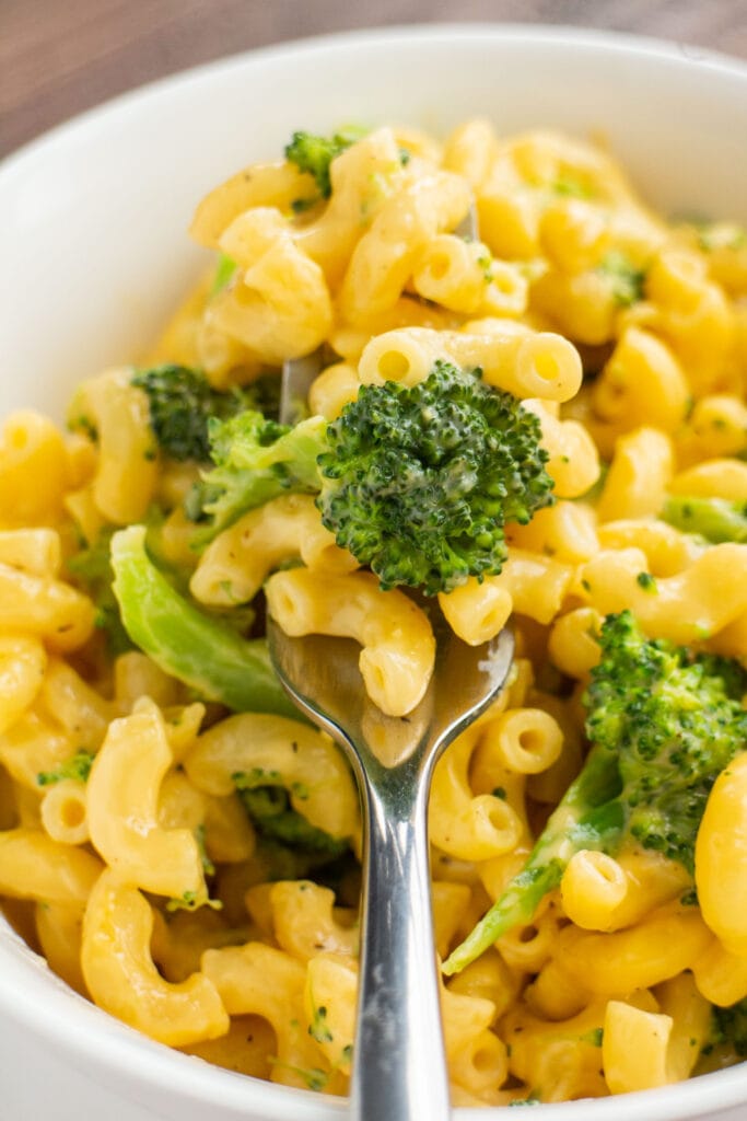 spoon holding broccoli and cheese in bowl. 