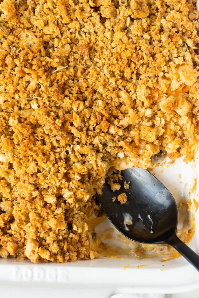 spoon serving carrot casserole out of white baking dish.