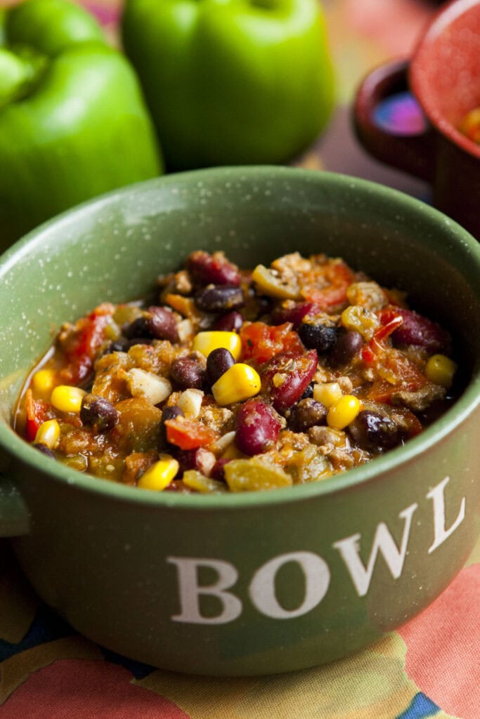 pumpkin chili filled with beans in green bowl. 
