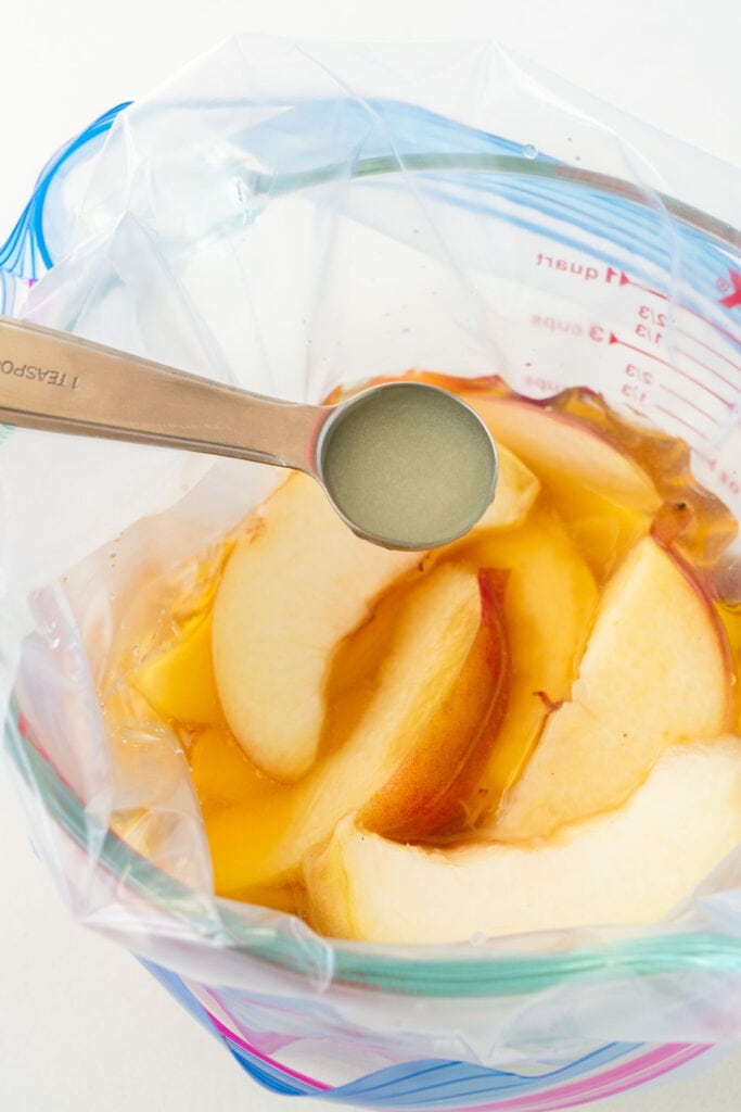 lemon juice added into measuring cup with peaches.