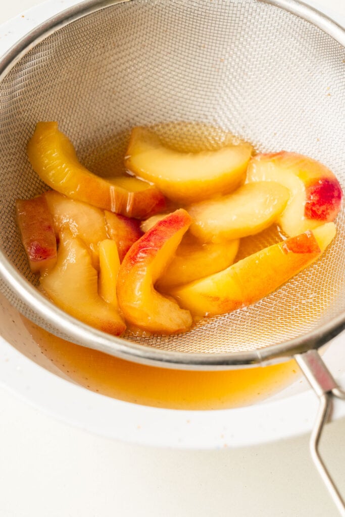 peaches over strainer with juices.