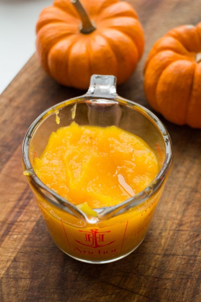 measuring cup of pumpkin puree on wooden background